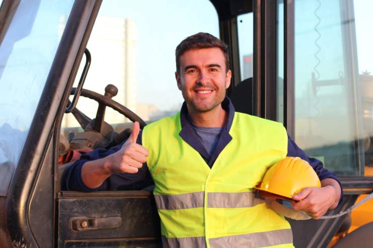 Un lavoratore con un elmetto da lavoro sottobraccio che sorride