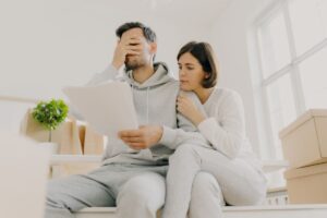 Uomo si copre il viso con foglio in mano, donna dietro di lui