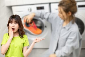 donna con scarpe in mano accanto la lavatrice e un'altra sorpresa