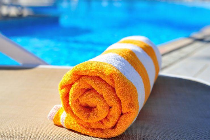 telo da mare arancione e bianco arrotolato su bordo piscina