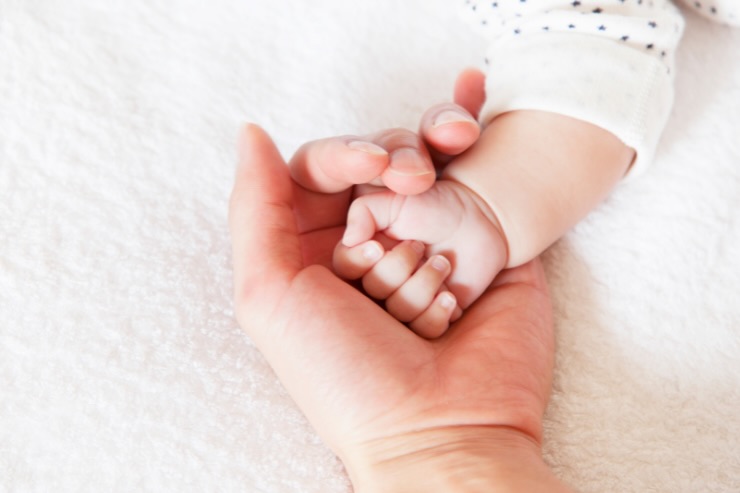 mano di mamma che tiene mano di bebè
