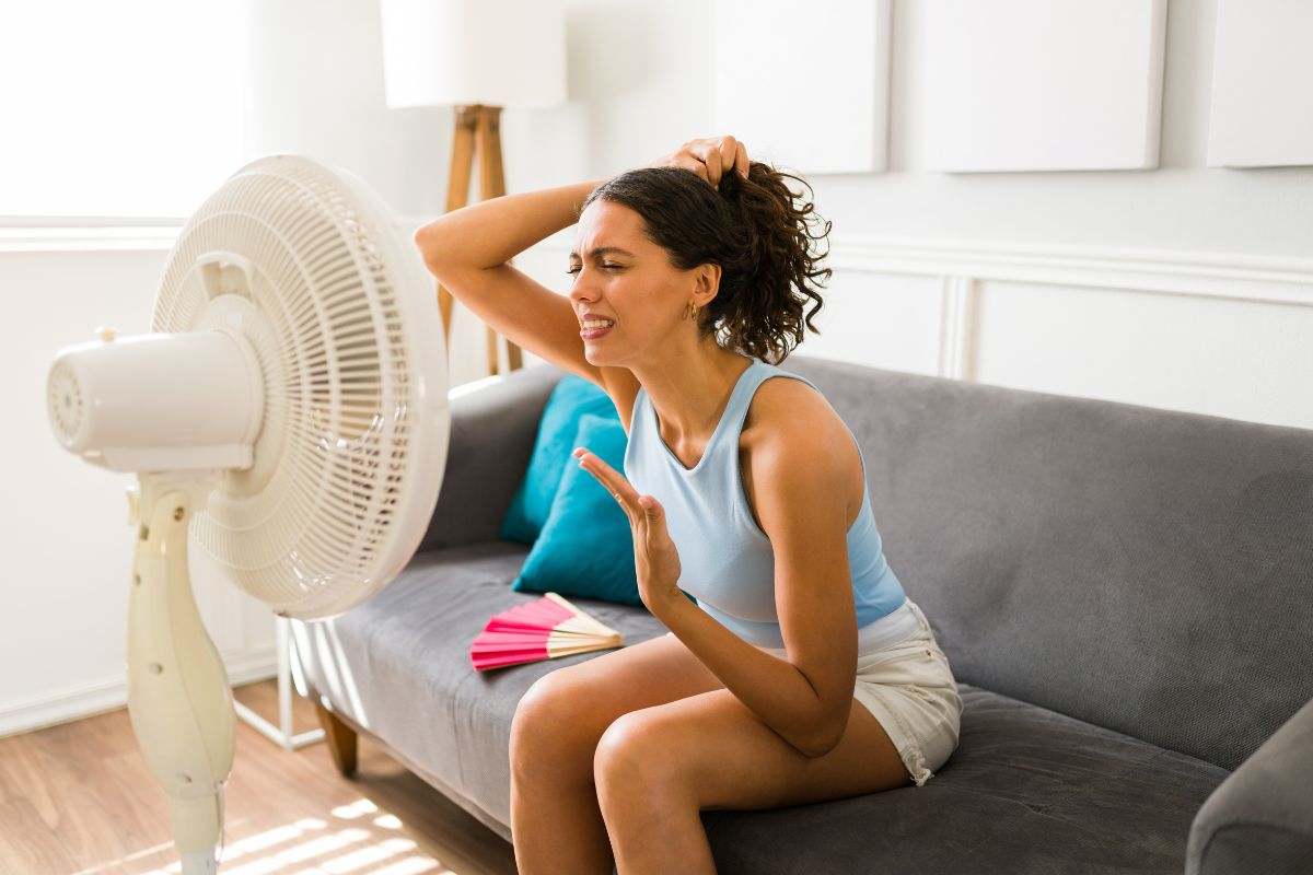 una persona che sente caldo e sta vicino al ventilatore