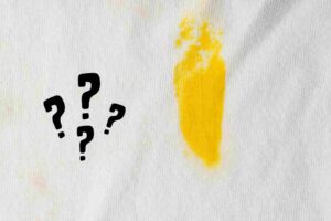 una macchia di olio su tessuti e vicino dei punti interrogativi