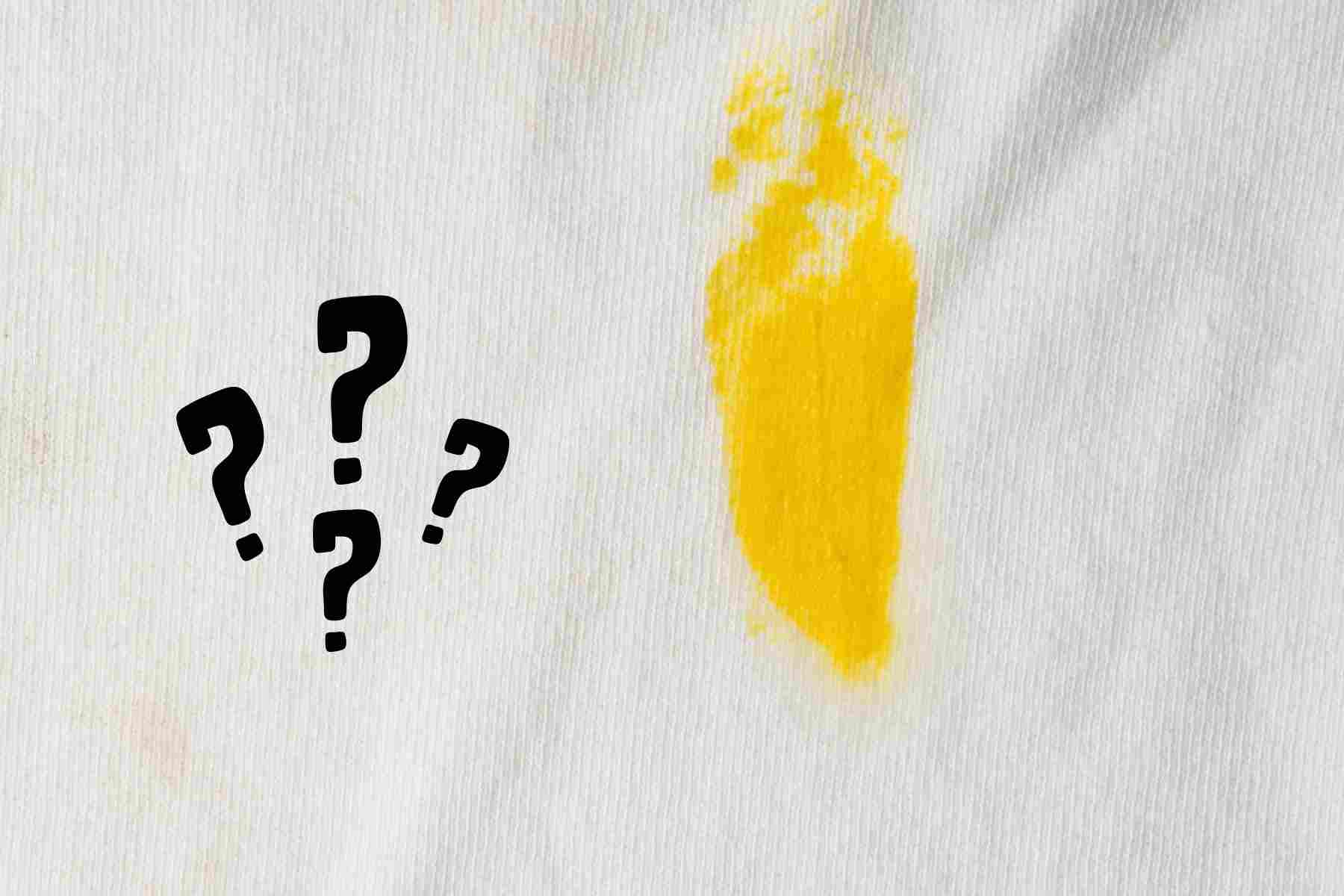 una macchia di olio su tessuti e vicino dei punti interrogativi