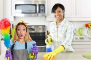 donna che pulisce la cucina e un'altra delle pulizie parecchio sorpresa