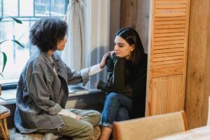 Due ragazze che parlano ed una (quella a sinistra) cerca di dare forza e conforto all'altra ragazza (quella a sinistra)