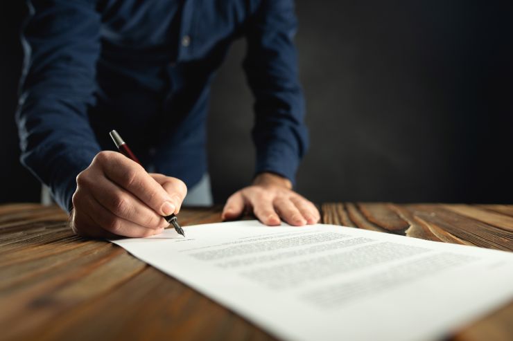uomo che compila dei moduli con una penna