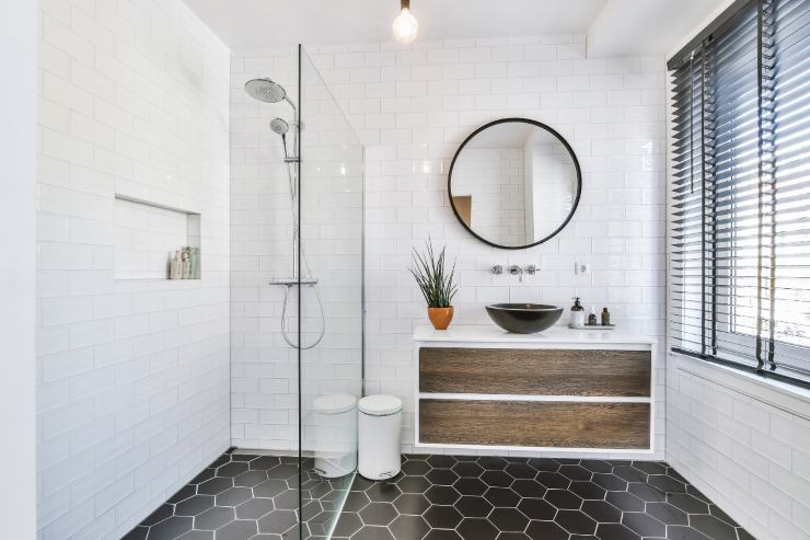 un bagno moderno con pavimento nero e vetro rotondo