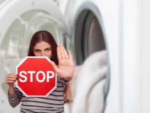 asciugamani in lavatrice e donna con cartello di stop tra le mani