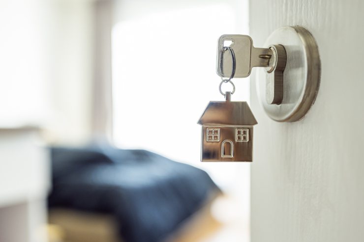 una porta semiaperta con le chiavi appese e si intravede un letto
