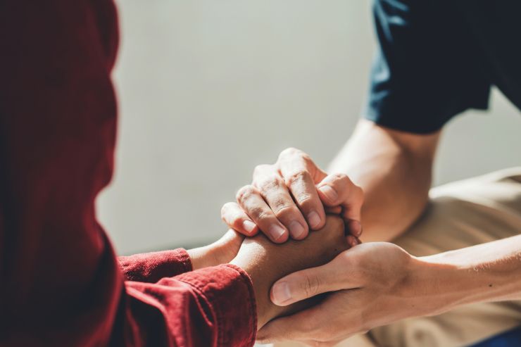 due persone che si stringono le mani in segno di supporto e conforto