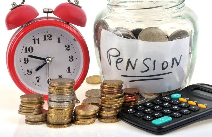 una sveglia, un barattolino con i soldi e la scritta pensione, ed una calcolatrice