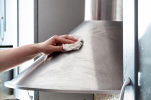 persona che sta pulendo con un panno la cappa della cucina