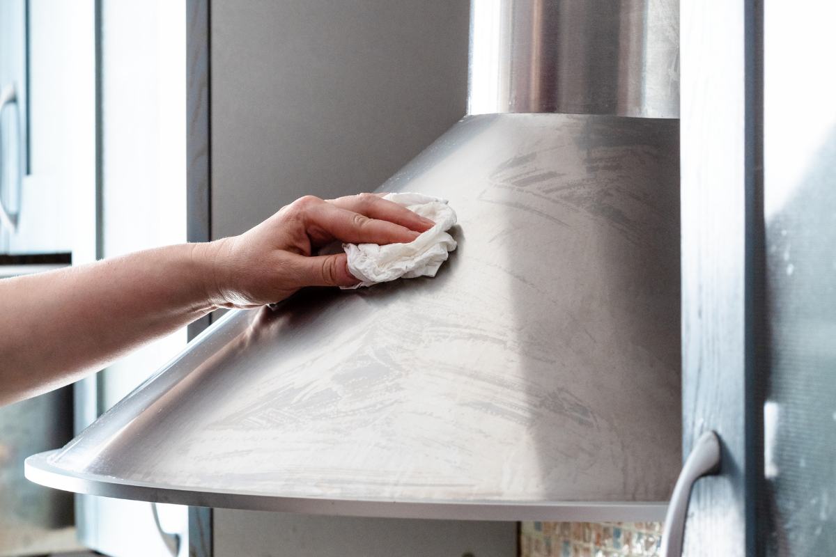 persona che sta pulendo con un panno la cappa della cucina