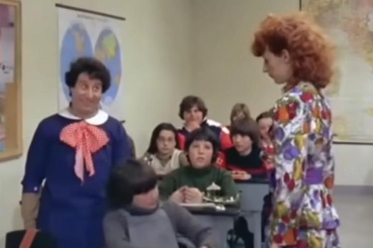 una foto di una scena di "Pierino".Pierino in classe che parla con la maestra di fronte la classe