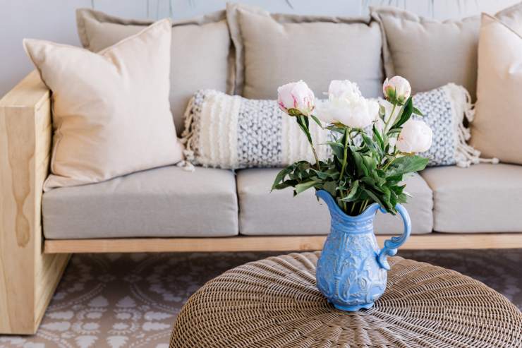 Un salone con un divano e davanti un tavolino con sopra un vaso di fiori