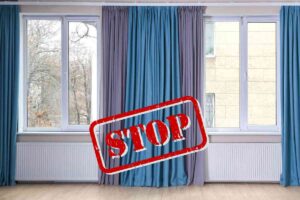 finestre con le tende con davanti una scritta in rosso "STOP"