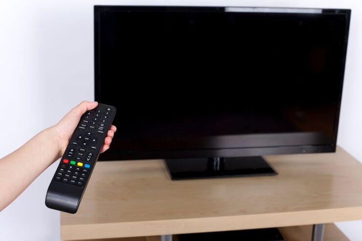 Telecomando in mano e televisore