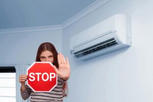 un condizionatore e una ragazza che tiene in mano un cartello Stop