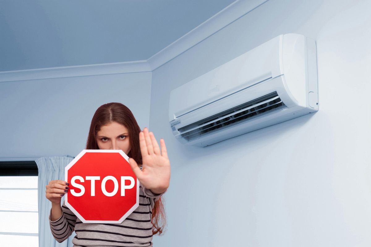 un condizionatore e una ragazza che tiene in mano un cartello Stop
