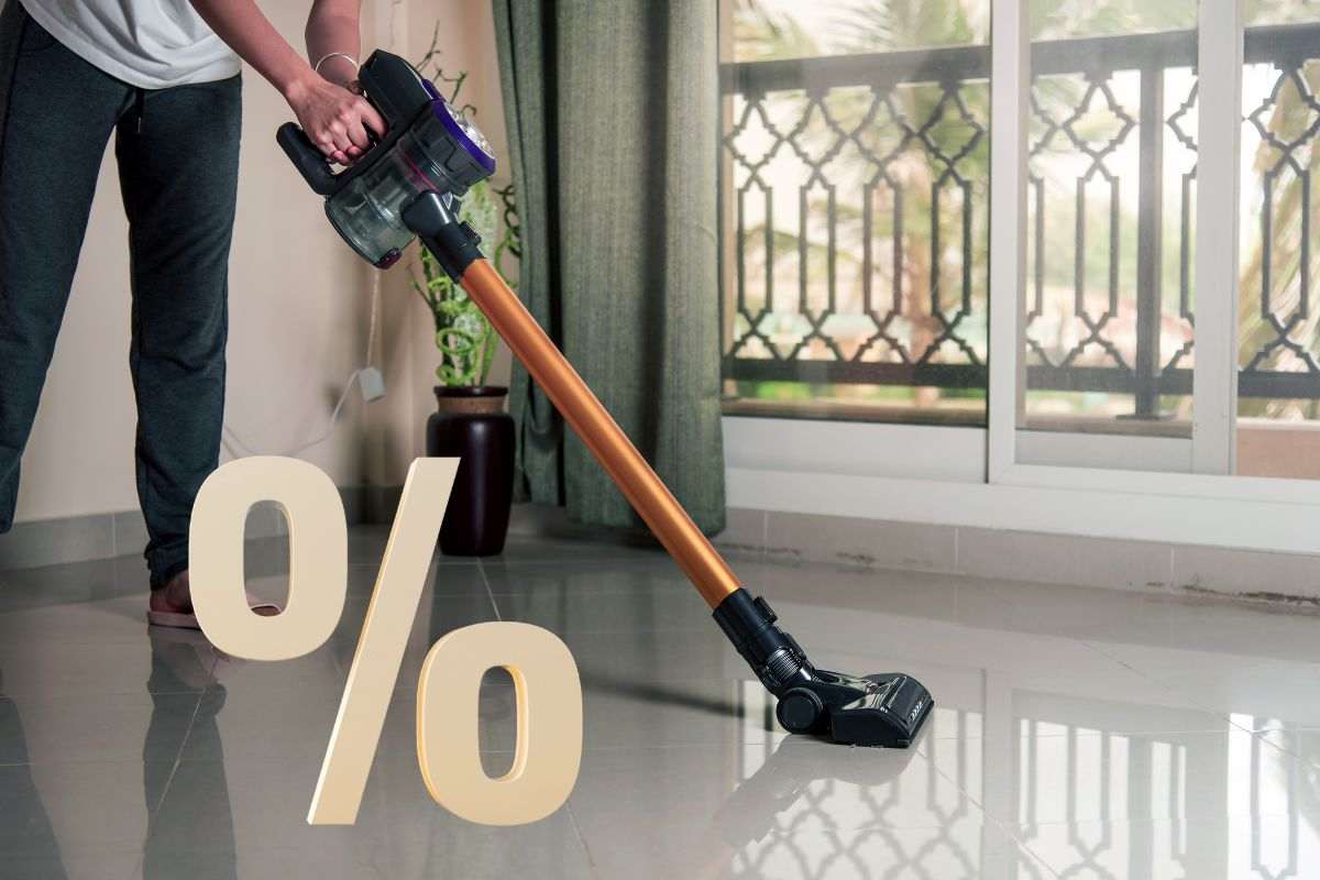 una persona che pulisce con un'aspirapolvere senza fili e la percentuale
