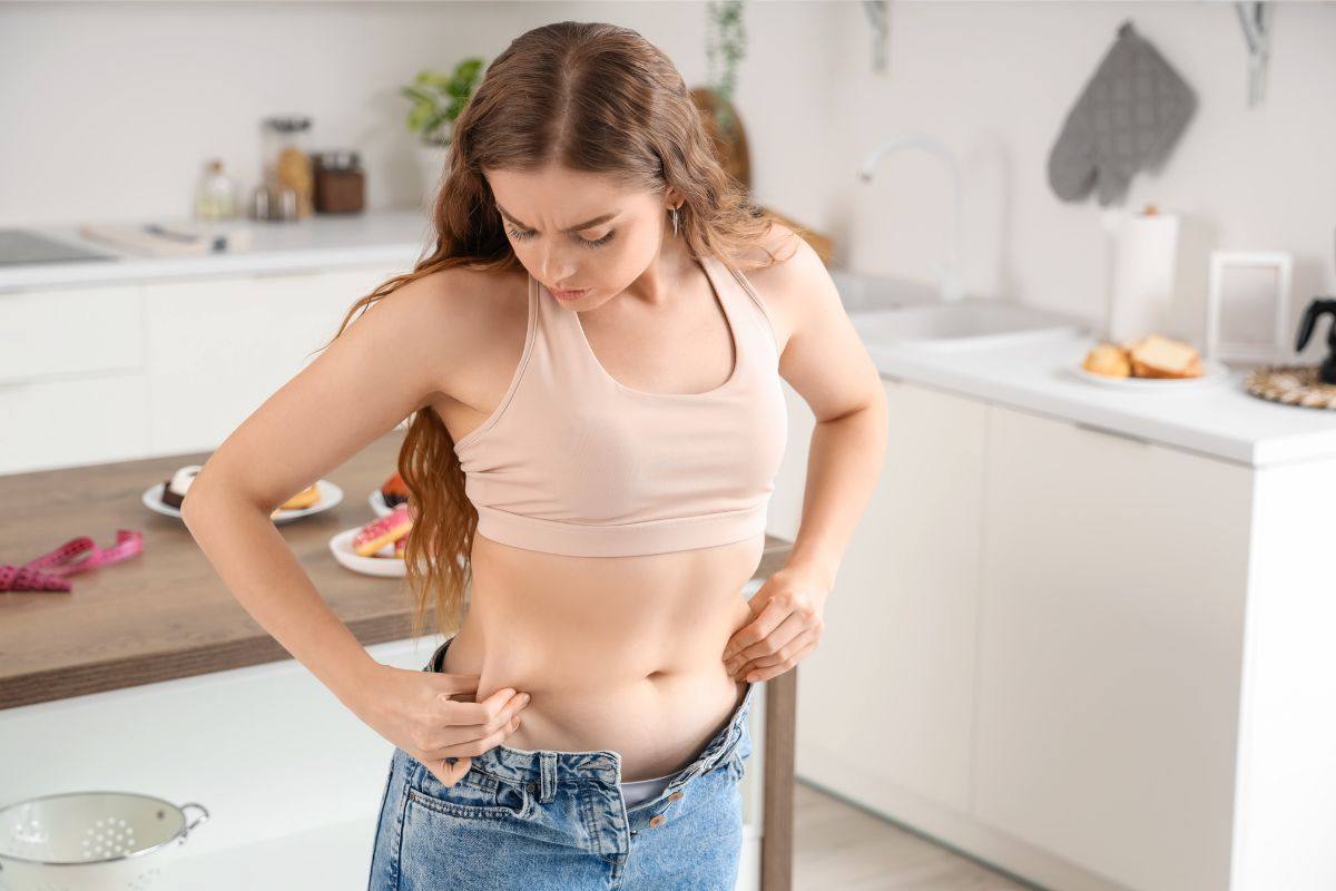 una ragazza che non riesce ad allacciarsi i pantaloni