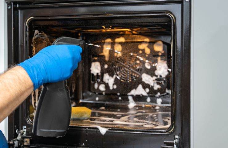 donna che pulisce forno con detersivi