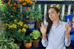 Donna contrariata mani alzate, piante in vasi nel balcone