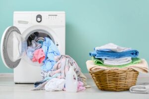 lavatrice con i panni e cesta dei panni sulla sinistra