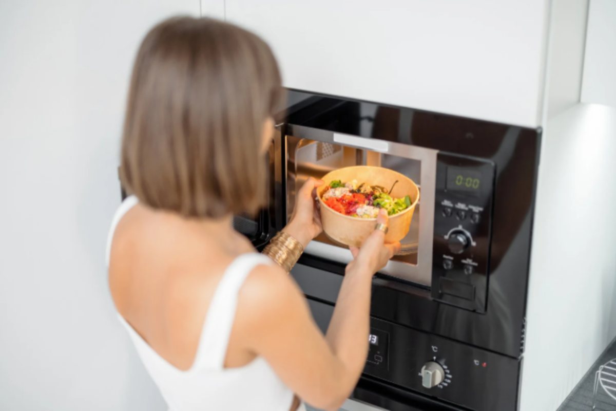 donna che mette del cibo nel microonde