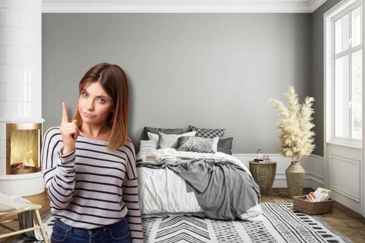 donna con dito in alto e camera da letto