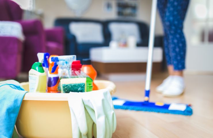 kit di pulizie e donna che pulisce casa