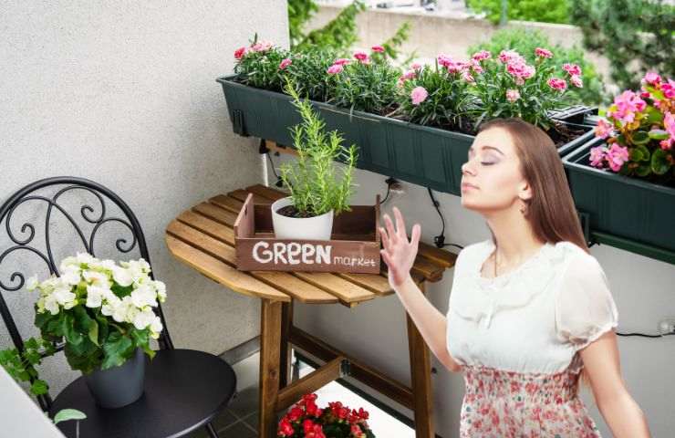balcone fiorito con una ragazza che odora