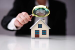 una persona che tiene in mano una lente di ingrandimento sopra una casa piccola
