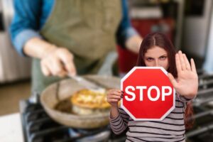 donna che cucina e un'altra che fa stop con le mani