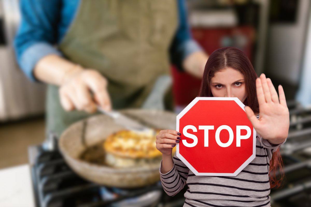 donna che cucina e un'altra che fa stop con le mani