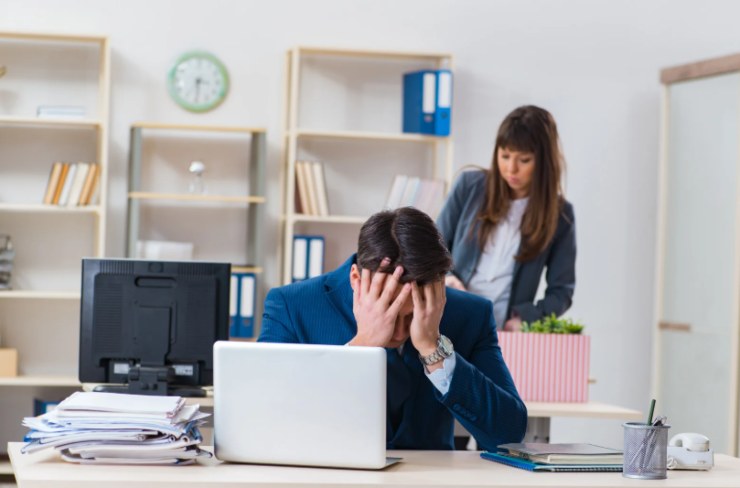 lavoratore disperato seduto alla scrivania con la mani in faccia