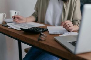 Donna che fa i calcoli alla scrivania con pc e calcolatrice