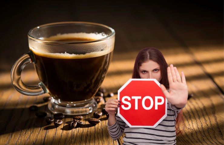 una tazza di caffè e una persona con il cartello stop in mano