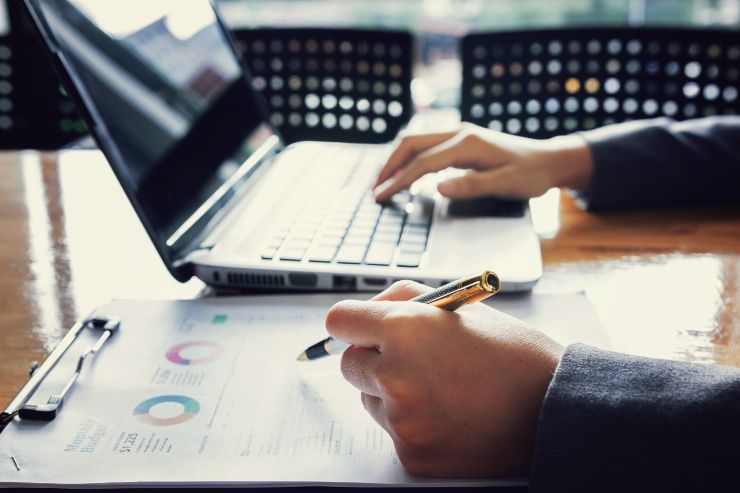 amministratore su una scrivania che fa ricerca sul computer e analizza dati.