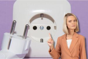Donna con dito alzato, dietro di lei presa della corrente e spina