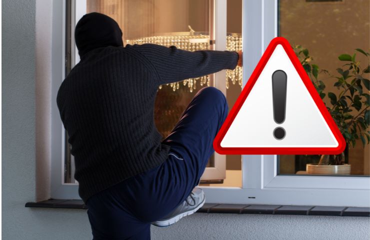 un ladro che entra in casa e il simbolo attenzione
