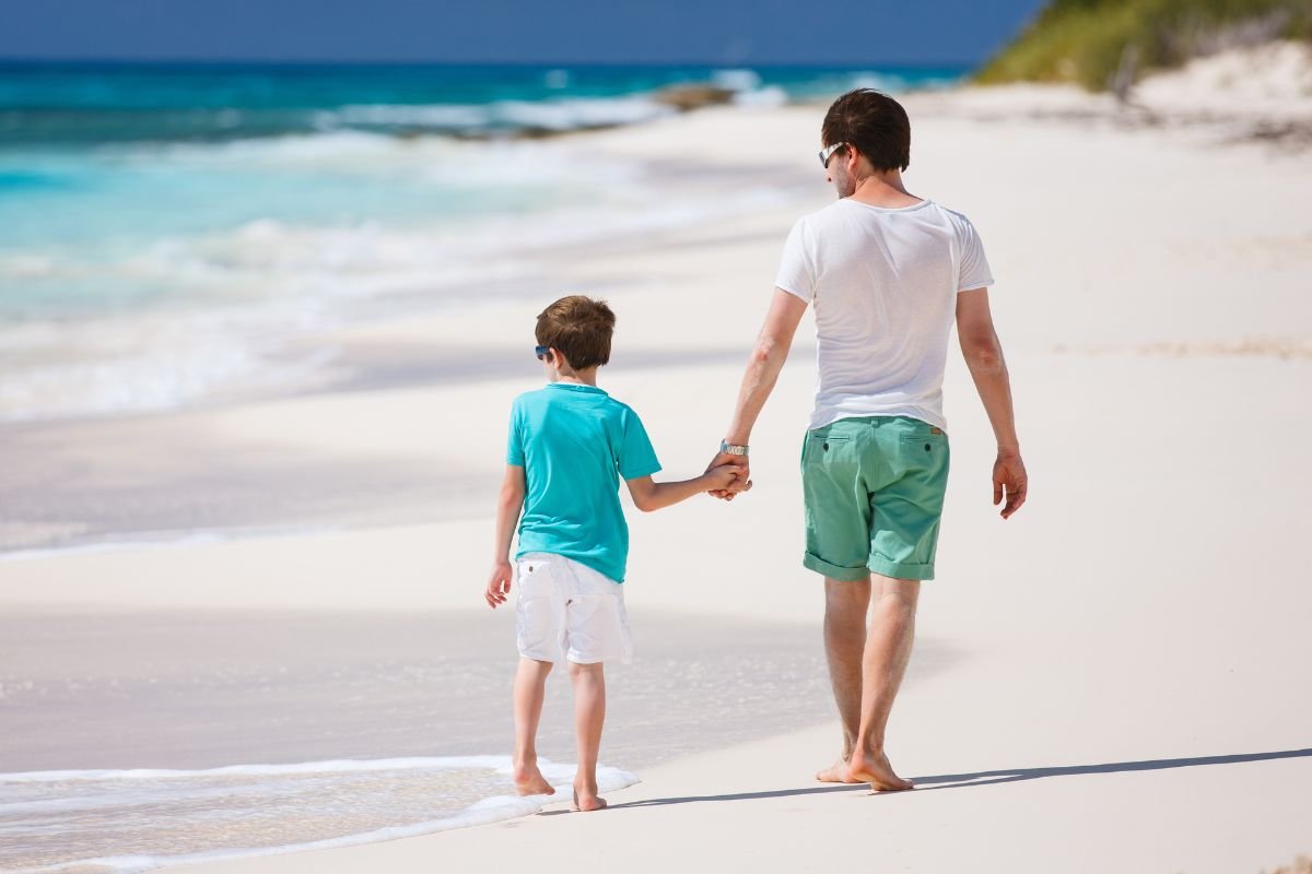 un papà e il figlio che passeggiano sulla spiaggia